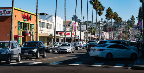 Cars on street in city against clear blue sky