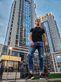 Low angle view of man standing against modern buildings in city