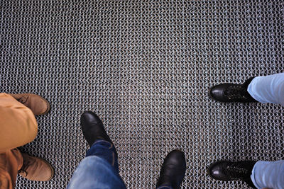 Low section of people standing on metallic floor. jeans and shoes.