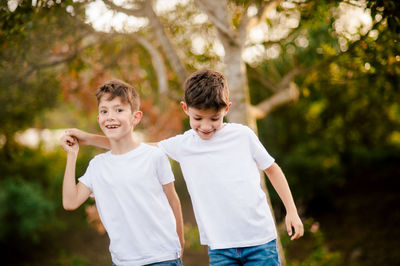 Happy twin boys hugging and looking at camera in park