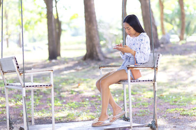 Woman using mobile phone while sitting on chair