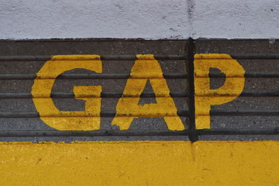 Close-up of yellow arrow sign on wall