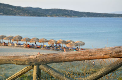 Greek blue sea and parasols on the beach behind wooden fence