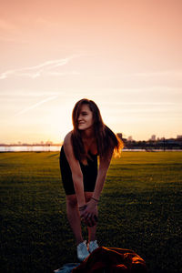 Woman on field against sky during sunset