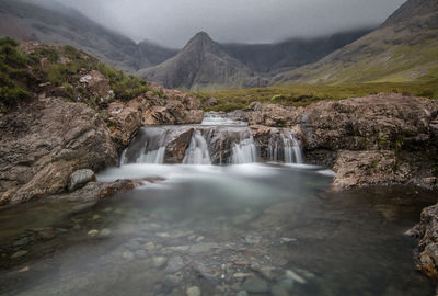 Scenic view of waterfall against mountains