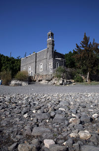 Stone wall by building against clear blue sky