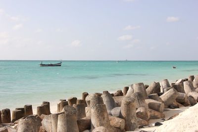 Scenic view of concrete blocks on beach against cloudy sky