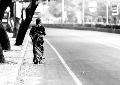 Full length rear view of woman walking on street