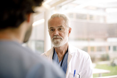 Contemplating wrinkled nurse talking to male colleague in hospital