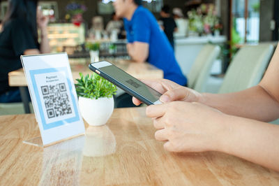 Midsection of woman holding smart phone on table