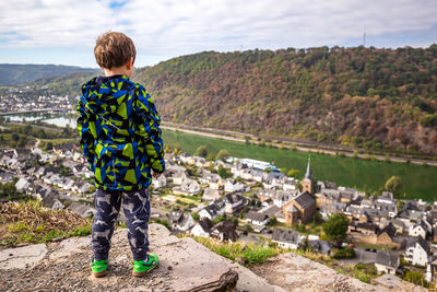 Rear view of boy standing on mountain against sky