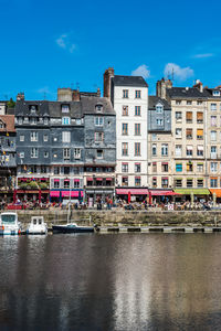 River by buildings against blue sky