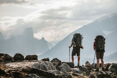 Rear view of people standing on rock against sky