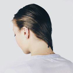 Rear view of woman with wet hair against white background