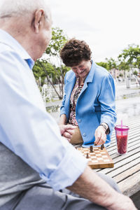 Senior couple sitting on a bench playing chess