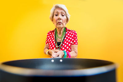 Portrait of woman standing against yellow background