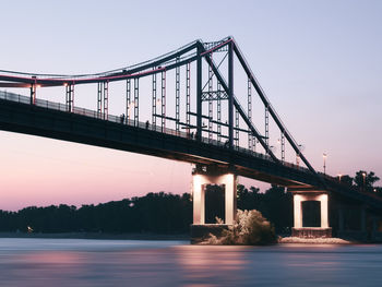 Low angle view of bridge over river against clear sky at dusk