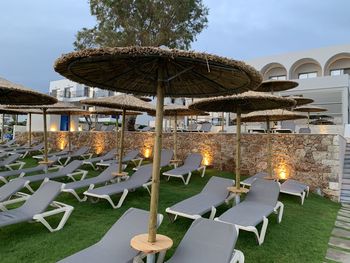 Chairs and tables at swimming pool against sky