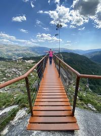 Full length of woman walking on footbridge over landscape