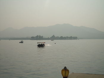 Boats in calm sea against mountain range