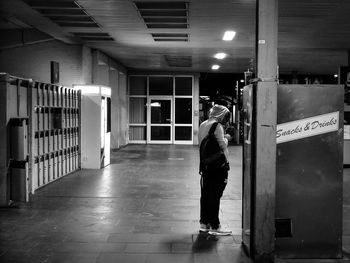 Man standing by snack vending machine at railroad station