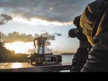 Man photographing working against sky during sunset