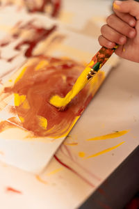 Cropped hand of woman painting on table