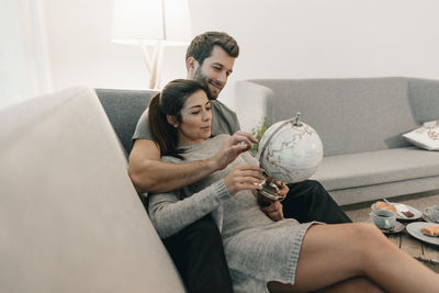 Couple relaxing on couch at home looking at globe