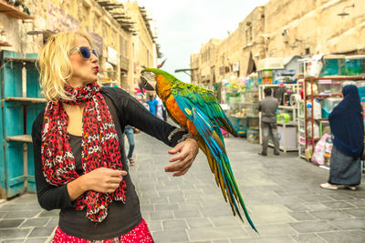 Woman with bird standing in city