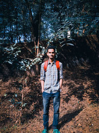 Full length portrait of young man standing in forest