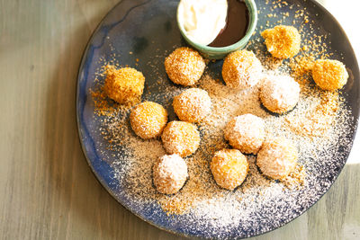 Cheese balls in breadcrumbs on a plate with sour cream sauce and jam