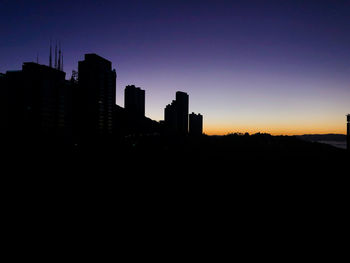 Silhouette buildings against clear sky at sunset