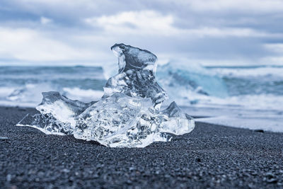 Close-up of beautiful iceberg chunk on black sand of diamond beach against sky