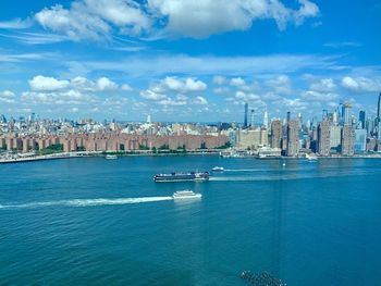 View of buildings in city at waterfront against cloudy sky