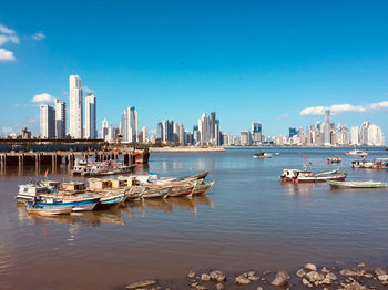 Boats moored in sea against buildings in city