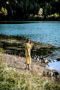 Woman standing by lake against plants