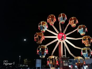 Low angle view of illuminated ferris wheel against sky at night