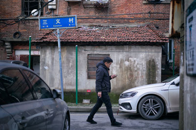 Man standing by car on city street