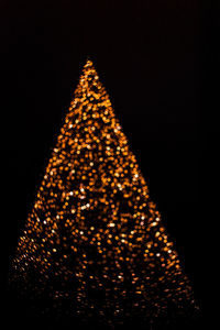 Low angle view of illuminated christmas tree against sky at night