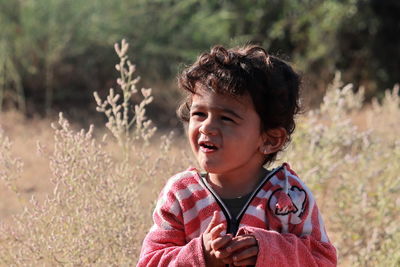 A beautiful little indian child stands in the field and the natural blur background of white bushes