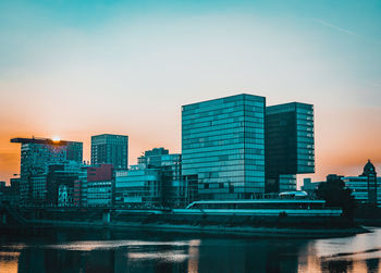 Modern buildings in city against sky during sunset