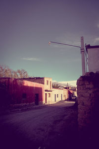 Road by buildings against sky in city