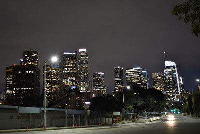 Illuminated city buildings against sky at night