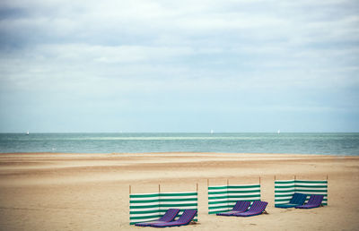 Chairs on beach against sky