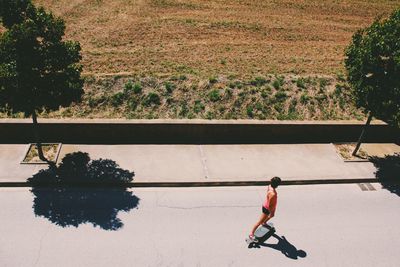High angle view of woman skateboarding on road during sunny day