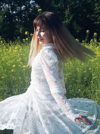 Woman in a white dress in a field of yellow flowers