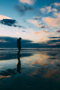 Silhouette man standing on beach against sky during sunset