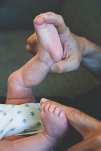 Cropped hand of father holding baby feet at home