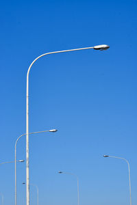 Low angle view of street lights against blue sky