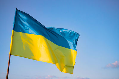 Low angle view of flag against clear blue sky